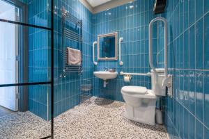 a blue tiled bathroom with a toilet and a sink at Sailors Rest in Appledore