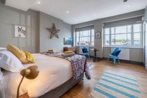 a bedroom with a large bed and blue chairs at Sailors Rest in Appledore