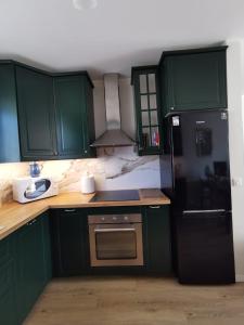 a kitchen with green cabinets and a black refrigerator at Milusi Domek in Łagów