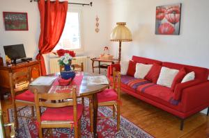 salon z czerwoną kanapą i stołem w obiekcie Au Petit Bonheur w mieście Thannenkirch