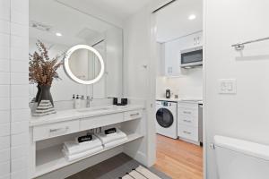 a white bathroom with a sink and a washing machine at The Iris in Charleston