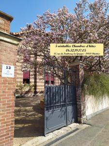a gate to a brick building with a flowering tree at L'Echappée Belle in Chartres