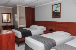 マチャラにあるGrand Hotel Machalaのベッド2台とテーブルが備わるホテルルームです。