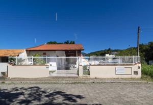 una cerca blanca frente a una casa en CASA JACUÍ A 350 METROS DA PRAIA, en Bombinhas