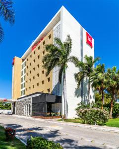 un hotel con palmeras delante en Ibis Merida, en Mérida