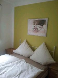 uma cama com almofadas brancas e um quadro na parede em Liebevoller Landhaustraum em Ratekau