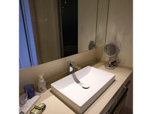 lavabo blanco en el baño con espejo en Miyakojima Kurima Resort Seawood Hotel - Vacation STAY 16234v en Uechi