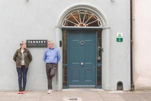Un uomo e una donna in piedi davanti a una porta di Tannery Townhouse a Dungarvan