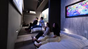 eine Gruppe von Personen, die in einem Zimmer auf Betten sitzen in der Unterkunft trive ozone - Vacation STAY 25323v in Nagoya