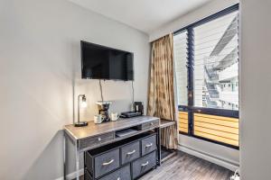 a room with a dresser with a tv and a window at Inviting Waikiki Grand Hotel Room One Block to Beach! in Honolulu