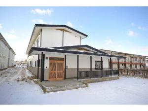 un edificio bianco con una porta di legno nella neve di Guest House Tou - Vacation STAY 26356v a Kushiro