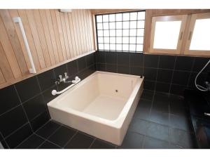 a white bath tub in a black tiled bathroom at Guest House Tou - Vacation STAY 26359v in Kushiro