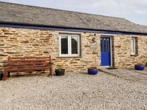 a stone cottage with a bench in front of it at Wheal Rose in Newlyn East