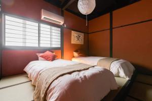 大阪市にあるOyado NAKAZ II - Vacation STAY 27698vのオレンジ色の壁と窓が備わる客室で、ベッド2台が付いています。