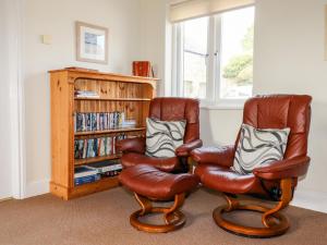 dos sillas de cuero sentadas junto a un estante de libros en Wheal Hart en Newlyn East