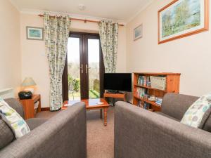 a living room with two couches and a tv at Honeysuckle Cottage in Bude