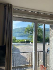 a sliding glass door with a view of a body of water at Borrodale, one bedroom apartment with balcony and loch view. in Fort William
