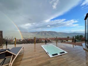 una piscina en una terraza con un arco iris en el fondo en Glamping El Regajo Valle del Jerte en El Torno