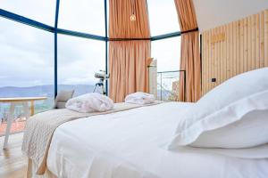 a bedroom with a white bed with large windows at Glamping El Regajo Valle del Jerte in El Torno