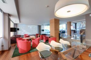 um átrio com cadeiras e mesas vermelhas e brancas em Hotel Vigo Los Galeones Affiliated by Meliá em Vigo