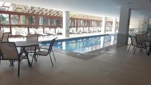 a swimming pool with chairs and tables and a table and a pool at Flat Vista Azul Hotel in Pedra Azul