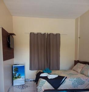 a bedroom with a bed and a window with a curtain at Hotel Pousada Paraíso Tropical in Salinópolis
