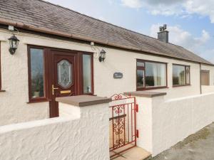 Casa blanca con puerta y ventanas marrones en Llys Llywenan, en Bodedern