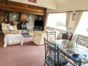 a living room with a glass table and a fireplace at Llys Llywenan in Bodedern