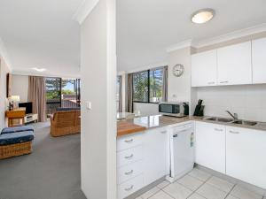 een keuken met witte kasten en een woonkamer bij Aries Unit 5 in Gold Coast