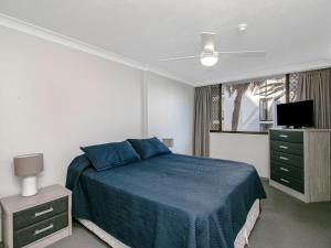 een slaapkamer met een blauw bed en een televisie bij Aries Unit 5 in Gold Coast