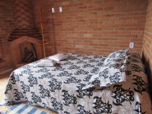 a bed in a room with a brick wall at CHALÉ Nativo R do Céu nº 106 in Conceição da Ibitipoca