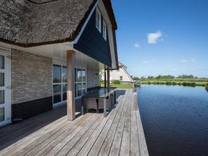 una casa con un molo accanto a un bacino d'acqua di Spacious villa with two saunas, on the Tjeukemeer a Delfstrahuizen