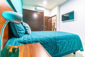 1 dormitorio con 1 cama con manta azul y mesa en Departamento con Alberca, Jacuzzi y Vista al Mar en Mazatlán