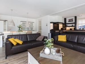 een woonkamer met een zwarte bank en gele kussens bij Spacious villa with two saunas, on the Tjeukemeer in Delfstrahuizen