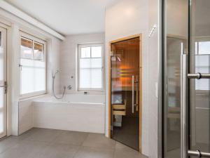 a bathroom with a bath tub and a shower at Villa in Friesland with Sauna and Whirlpool in Delfstrahuizen +33 photos