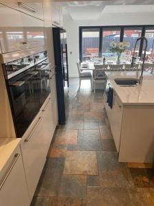 uma cozinha com armários brancos e piso em azulejo em Luxury Portrush Holiday Homes - The Glynn, Portrush Sleeps 12 - 5 bedrooms em Portrush
