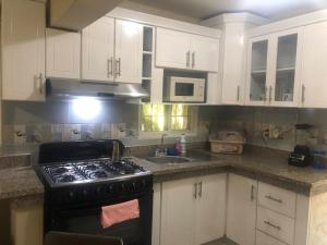 uma cozinha com armários brancos e um forno com placa de fogão em Apartamento CGM de 1 habitación em La Romana