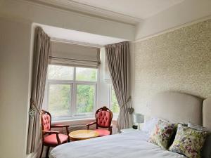 a bedroom with a bed and two chairs and a window at The Wentworth Guest House in Paignton