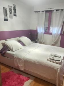 a bedroom with a large white bed with a pink rug at Logement entier+ jardin privé et parking 2places in Rouen