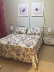 sypialnia z łóżkiem z narzutą w kwiaty w obiekcie Apartamento Loyola Tania w mieście Conil de la Frontera