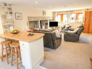 a living room with couches a table and a fireplace at Stables Cottage in Todmorden