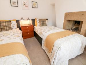 two twin beds in a room with a fireplace at Rose Cottage in Bakewell