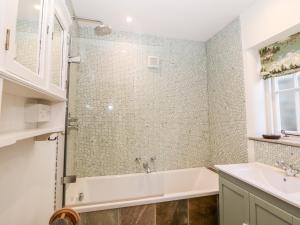 a bathroom with a bath tub and a sink at Rose Cottage in Bakewell