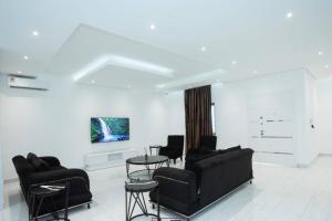 sala de estar con sillas negras y pared blanca en Banner Vacation Home & Swimming Pool en Prampram