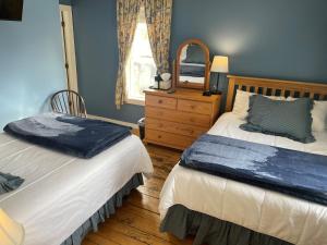 a bedroom with two beds and a mirror and a dresser at Smugglers Notch Inn in Jeffersonville