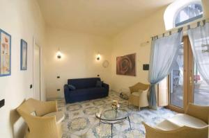 a living room with a blue couch and chairs at Terrazza di Rosa - sea view in Praiano