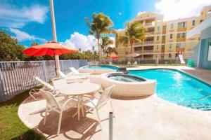a table and chairs with an umbrella next to a swimming pool at 3Bedrm Beach Penthouse with Rooftop Terrace & WiFi in Rio Grande