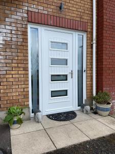 uma porta de garagem branca numa casa de tijolos em Luxury Portrush Holiday Homes - The Glynn, Portrush Sleeps 12 - 5 bedrooms em Portrush
