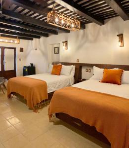 a bedroom with two beds with orange blankets on them at Kuxtal Hotel Boutique in Mérida