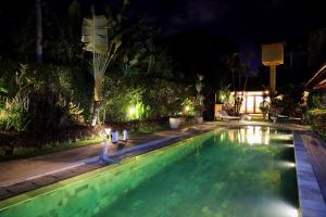a swimming pool in a backyard at night at Sasa Bali Villas in Seminyak